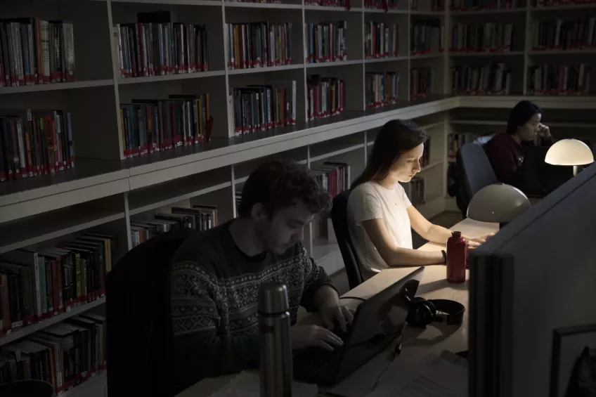 Studenter på Samhällsvetenskapliga biblioteket i mörker med små lampor. Foto.